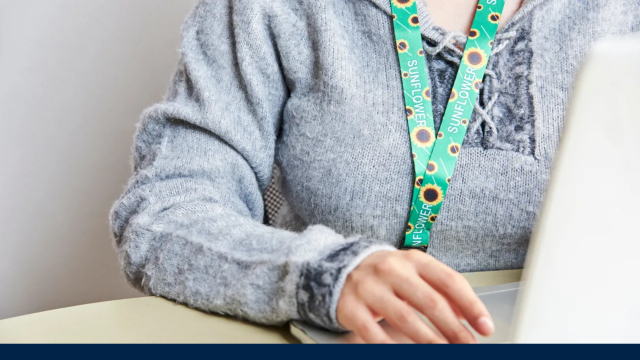 Image from the associated article depicts a person sitting at a desk with a sunflower lanyard clearly displayed hanging around their neck