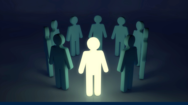 A bright glowing figure stands out in the dark amongst a group of other figures.