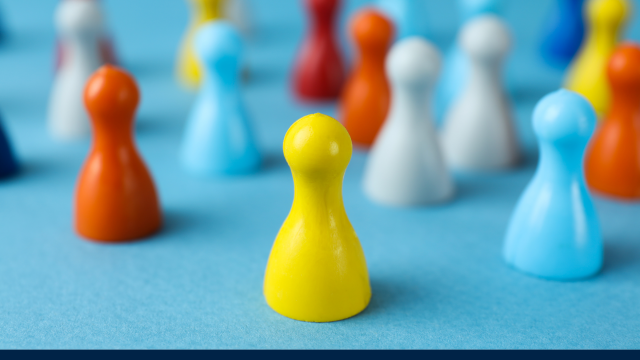 Image shows small pawn-like pegs in various colours on a blue surface