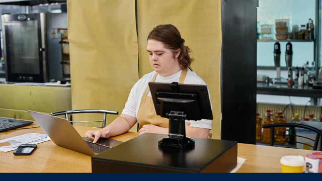 Image taken from an article depicts a young girl with Down's Syndrome sitting at a desk, typing on a laptop.
