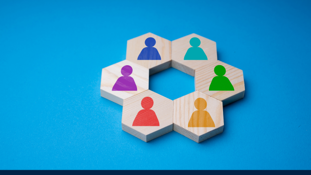 A pattern of wooden blocks in a circular pattern, each one featuring a painted human shape in different colours.