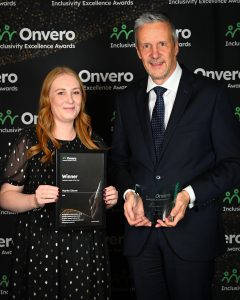Martin Glover accompanied with his colleague, Ailsa, posing in front of the step and repeat banner proudly displaying his trophy and certificate.