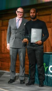 DEI Influencer of the Yea, Yohanes Scarlett, poses with Tom Berry on the stage at the ceremony.