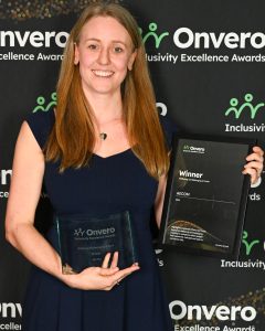 Claire from AECOM posing with her trophy and certificate in front of the step and repeat banner.